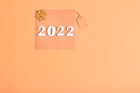 Craft postcard and wooden natural New Year's toys, numbers 2022 on a beige background, copy space....