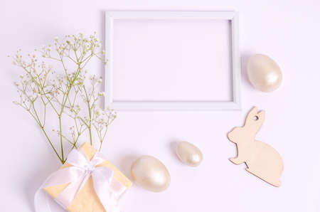 Easter egg and a wooden hare with a branch of hepsophila on a gift box on a white background. The concept of seasonality, spring, postcard, holiday. Flat lay, copy space, place for text.の写真素材