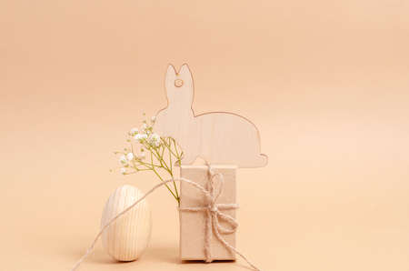 Easter egg and a wooden hare with a branch of hepsophila on a gift box on a white background. The...