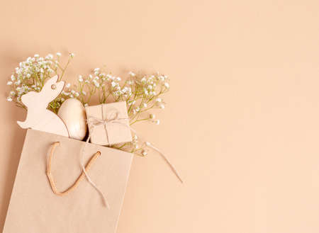 Easter egg and a wooden hare with a branch of hepsophila on a gift box on a white background. The...