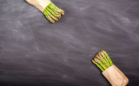 Stems of green fresh asparagus on a black background. Seasonal spring harvest. Flat lay, copy space. Healthy food concept. view from above.の写真素材