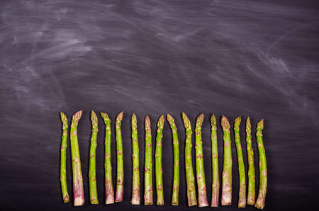 Stems of green fresh asparagus on a black background. Seasonal spring harvest. Flat lay, copy space. Healthy food concept. view from above.の写真素材