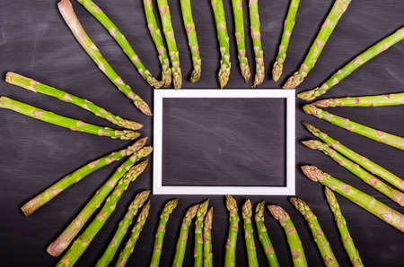 Stems of fresh green asparagus on a black background with place for text. Seasonal spring harvest. Flat lay, copy space. Healthy food concept. close-upの写真素材