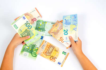 Euro paper banknotes of different denominations in a child's hand on a white background. The concept of money, economy, finance, savings. close-upの写真素材