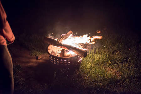 outside fire with a woman enjoying the warmth with a glass of wine with embers