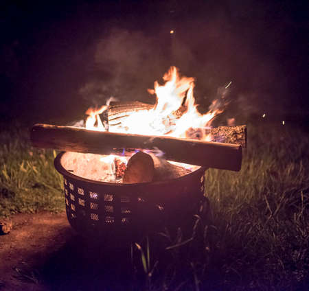 outside fire with a woman enjoying the warmth with a glass of wine with embers
