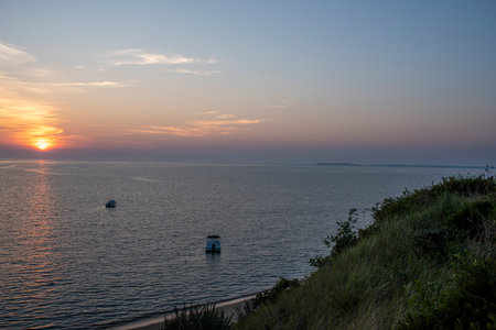 Cape Cod summer sunset over the bay with birds and boats bobbing around on the waterの写真素材