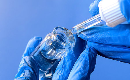hands of a lab technician with a tube of blood sample , lab assistant holds a blood test tube for...