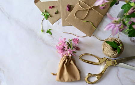 Marble desk with pink and blue flowers, postcard, kraft envelope, twine, cotton branch. Layout of...