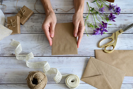 Marble desk with pink and blue flowers, postcard, kraft envelope, twine, cotton branch. Layout of Women's Day or Mother's Day, St. Valentine's Day, flat position, top view.の写真素材