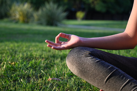 A girl in a white sports uniform does yoga with a belt in nature on a sunny summer day. A yogi conducts a yoga class in the fresh air.の写真素材