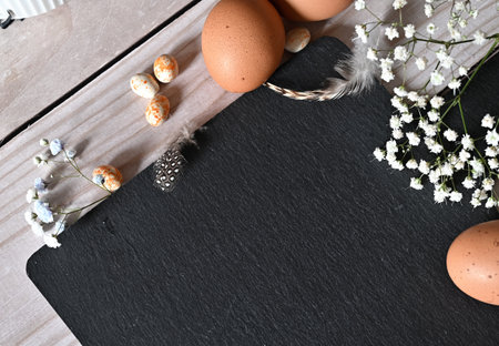 Create an Easter composition of Easter quail eggs and flowers on a white wooden background. A...