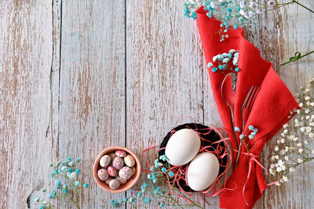 Create an Easter composition of Easter quail eggs and flowers on a wooden background. A gentle...