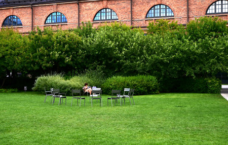 Attractive female in glasses, striped t-shirt and black jeans sitting in chair crossing her leg over the other. Charming woman enjoys the sunshine and warm day outdoor. Getting pleasure from life.の写真素材