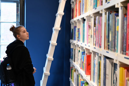 School girl looking at bookshelf in school library. Books on shelves in bookstore. Learning from books. back to school. elementary education. Benefits of everyday reading. Curious childの写真素材