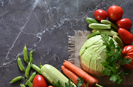 food cooking background. Fresh rosemary, cilantro, basil, cherry tomatoes, peppers and olive oil, spices herbs and vegetables at black slate table. Food ingredients top view.の写真素材