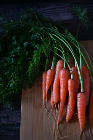 Top view of bunch of fresh organic rainbow carrots on black background representing concept of...