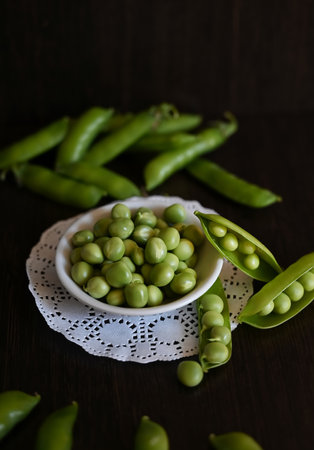 Green shoots of young peas, flowers and pods on a dark wooden background. selective focusingの写真素材