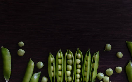 Green shoots of young peas, flowers and pods on a dark wooden background. selective focusingの写真素材