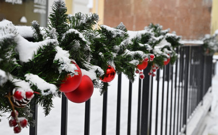 Red Christmas balls hanging on a fir branches covered by snow. New Year tree with decorations, magic of a holidayの写真素材