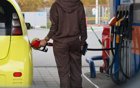 Pumping gas at the gas pump. The woman refuels the car. A woman at a gas station. A woman fuels a car with gasoline at a gas station. Fuel injection into the tank. Detail of a woman filling a car with diesel fuelの写真素材