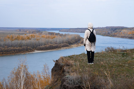 A woman stands on the edge of a cliff and looks at a nearby island, the sea. Unity with nature.の写真素材