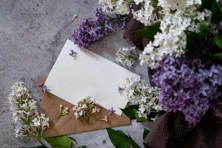 Composition with empty green envelope and beautiful spring lilac flowers on mint background. Mockup card invitation greeting card postcard copy space template. Branches of lilac blooming bouquet.の写真素材