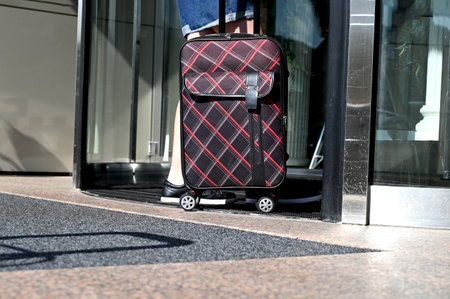 A young female traveler walking with a suitcase outdoors, rear view. Check-in at the hotel.