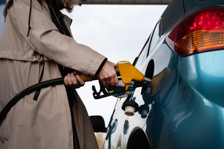 Pumping gas at the gas pump. The woman refuels the car. A woman at a gas station. A woman fuels a car with gasoline at a gas station. Fuel injection into the tank. Detail of a woman filling a car with diesel fuelの写真素材