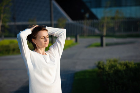 Young woman in formal clothes walking near gray wall outdoors, space for text