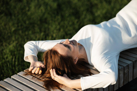 Headshot portrait of happy young woman outdoors. Teenager student girl smiling, turning her head in the sun, enjoying the weather with closed eyes. Millennial blonde girl relaxing in park, close-up.の写真素材