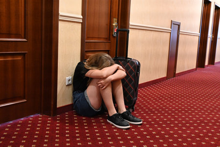 A woman sitting with a feeling of sadness while traveling with luggage on the floor.の写真素材