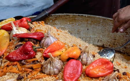 The cook puts hot delicious pilaf from the cauldron into a plastic plate. Asian street food