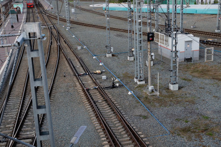 Railroad tracks stretch across the foreground, with a signal light indicating safe passage. Nearby,...