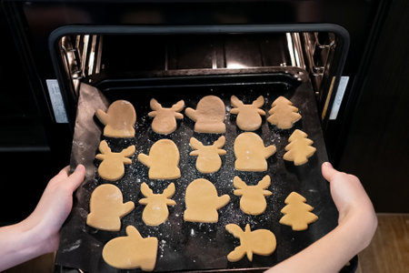Dough shaped like holiday figures sits on a baking tray as it is pulled out of the oven, ready to be transformed into delicious festive treats for celebrations.の写真素材