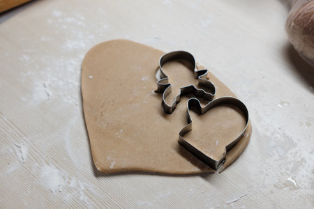 Dough shaped like holiday figures sits on a baking tray as it is pulled out of the oven, ready to be...