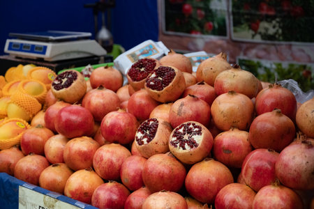 Large pile of pomegranates on counter of fruit market. bright juicy pomegranates as background. Close-up of a lot of ripe red pomegranates with specks on the market counter for saleの写真素材