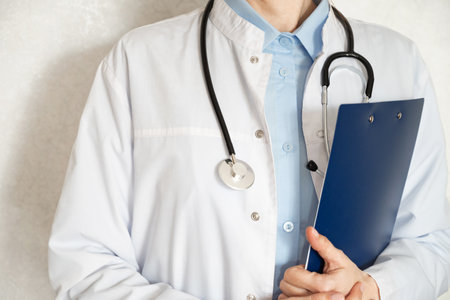 A healthcare professional is holding a clipboard and writing notes in a clinical environment. The...