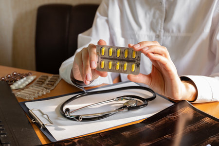 A healthcare worker in a teal shirt displays a collection of colorful pills and capsules in their hand. The setting emphasizes a focus on medication and health.の写真素材