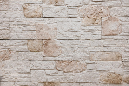 A surface of light-colored, textured stone blocks is arranged orderly, highlighting natural variations in tone and detail, creating a warm and inviting atmosphere.の写真素材