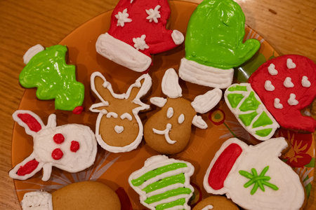 A person decorates a gingerbread cookie with vibrant green icing while seated comfortably in a warm living space. The atmosphere exudes festive cheer and creativity.の写真素材