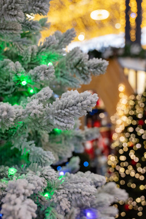 A snowy tree branch amidst festive lights. Background filled with colorful bokeh lights creating a cozy atmosphereの写真素材