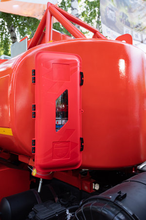 Close-up view of a red fire extinguisher container attached to an industrial vehicle, outdoors with...