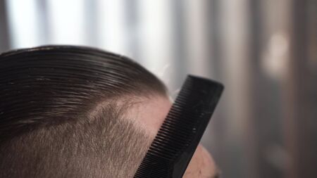 Following shot of comb on hair. Barbershop in city.