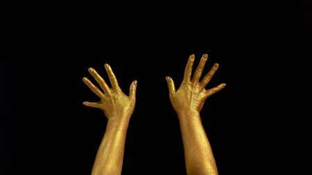 Nice footage of woman gold hands gesture. Black background. Hands in gold color paint on black backgroundの写真素材