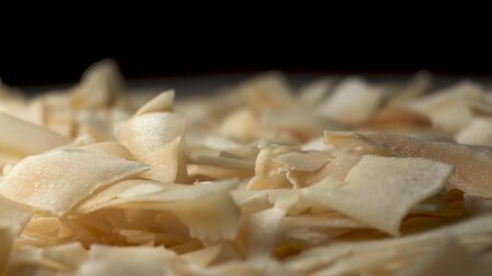 Coconut flakes lie on the table. Black background at the back. Coconut flakes rotate on a turntable, extreme close up macro footage.の写真素材