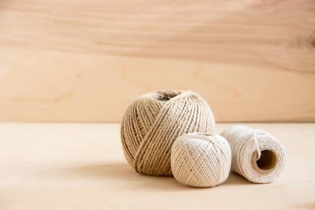 beige threads, twine on wooden background. Natural hemp rope spools on wooden table.
