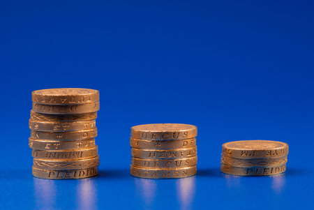 Descending stacks of coins on blue background 