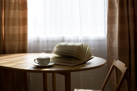 Open book and a cup of hot drink on a table