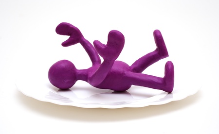 Purple man puppet of plasticine laying on plateの写真素材